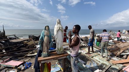 Un homme prie devant une statue de la vierge Marie parmi les d&eacute;combres de maisons d&eacute;truites par le gouvernement ivoirien dans le quartier de Port-Bou&euml;t&nbsp;&agrave; Abidjan (C&ocirc;te d'Ivoire), le 23 octobre 2014. (SIA KAMBOU / AFP)