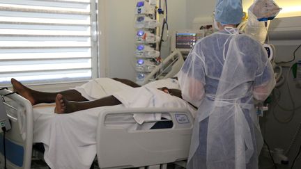 Un soignant aux côtés d'un patient atteint du Covid-19 au service réanimation de l'hôpital de Mamoudzou à Mayotte, le 11 juin 2020.&nbsp; (ALI AL-DAHER / AFP)