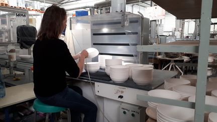 Une ouvrière travaille sur des bols en porcelaine de Limoges (Haute-Vienne). (NATHALIE COL / RADIO FRANCE)