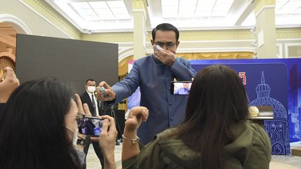 Le Premier ministre thaïlandais,&nbsp;Prayuth Chan-ocha, asperge des journalistes de spray hydroalcoolique, le 9 mars 2021, à Bangkok. (AP/SIPA)