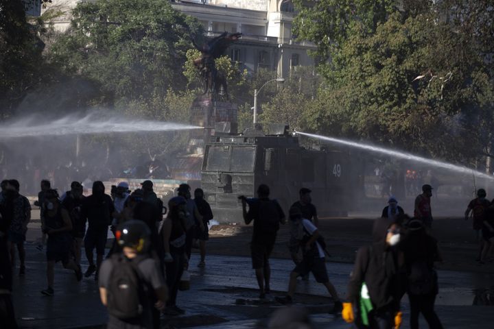 Les forces de l'ordre tentent de disperser une foule de manifestants à coups de jets d'eau, le 27 décembre 2019 à Santiago (Chili).&nbsp; (CLAUDIO REYES / AFP)