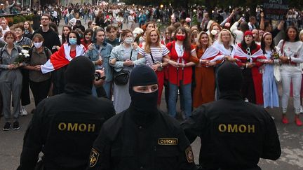 Des manifestantes à Minsk en Biélorussie le 29 août 2020, surveillées par des membres des forces de police. (EVGENY ODINOKOV / SPUTNIK / AFP)