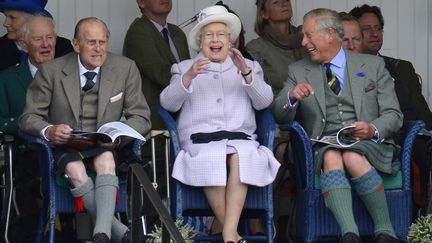 La reine Elizabeth (C), le prince Philip (G) et le prince Charles encouragent les participants lors d'une course en sac &agrave; Braemar (Royaume-Uni), le 1er septembre 2012. (RUSSELL CHEYNE / REUTERS)