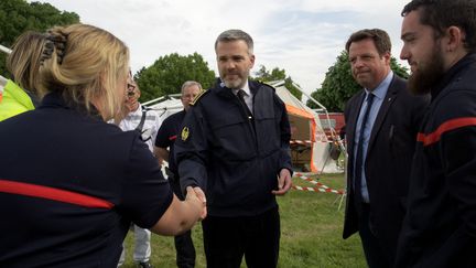 Le préfet de l'Indre, Stéphane Bredin, serre la main des pompiers lors du teknival organisé le 18 mai 2023 à Villegongis, malgré l'interdiction de la préfecture. (GUILLAUME SOUVANT / AFP)