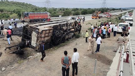 Des personnes devant le bus qui a eu un accident et a pris feu, le 1er juillet 2023 à Sindkhed Raja, dans l'Etat indien du Maharashtra. (GAJANAN MEHETRE / AFP)