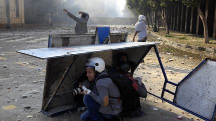 Un photographe se r&eacute;fugie dans un abri de fortune, alors que les affrontements entre manifestants et policiers &eacute;gyptiens se poursuivent au Caire, le 17 d&eacute;cembre 2011. (MOHAMMED ABED /&nbsp;AFP PHOTO)