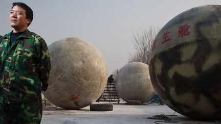 Liu Qiyuan pose devant les sphères anti apocalypse baptisées "Arche de Noé"
 (ED Jones / AFP)