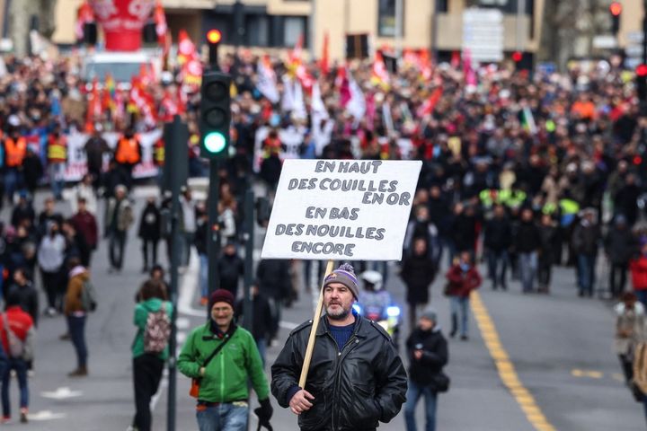 Cet homme descend les boulevards à Toulouse, ce jeudi 19 janvier, une pancarte au message fleuri sur l'épaule.&nbsp; (CHARLY TRIBALLEAU / AFP)