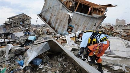 Dans la localité de Natori, le 14 mars, un secouriste scrute les décombres à la recherche d'éventuels survivants. (AFP - Toru YAMANAKA)