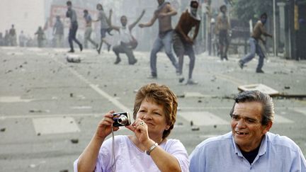 Un couple se tient devant une photo des &eacute;meutes de 2001 en Argentine expos&eacute;e pr&egrave;s du Congr&egrave;s &agrave; Buenos Aires (Argentine), le 19 d&eacute;cembre 2011. (MAXI FAILLA / AFP)