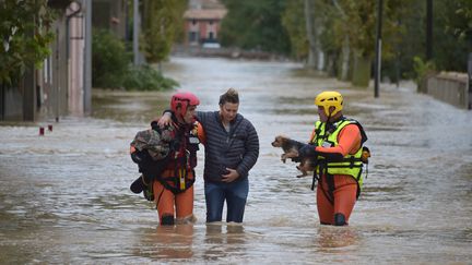 Des pompiers viennent en aide à une habitante de Trèbes (Aude) après les inondations, lundi 15 octobres 2018. (PASCAL PAVANI / AFP)