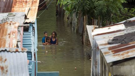 Après le passage de l'ouragan Matthew en République Dominicaine, des enfants avancent dans une rue inondée de La Puya, le 4 octobre 2016. (ERIKA SANTELICES / AFP)