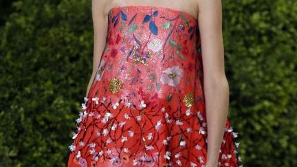 Pour sa 2e haute couture griffée Dior, Raf Simons voulait "une collection (qui) raconte l'idée même du printemps". Sous une tente installée aux Tuileries encore enneigé, Dior a reconstitué les allées d'un jardin avec des haies de buis au milieu desquels les mannequins sortaient du sol. La collection fourmille de fleurs rebrodées dans le tissu ou posées dessus par la magie des ateliers maison et des broderies Vermont que la griffe a rachetées en 2012. Les robes sont boules ou bustiers, courtes ou longues. Dans un tourbillon de soie et de tulles et de couleurs plutôt pastels, cette collection affirme son savoir-faire dans des millefeuilles de tulle jaillissant d'un côté, des superpositions, ou encore un manteau de soie écru sur une robe du soir bustier en soie brodée écrue qui donne envie d'aller au bal. 
 (FRANCOIS GUILLOT / AFP)