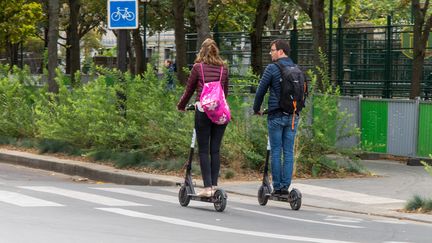 Deux personnes utilisent&nbsp;des trottinettes électriques, le 30 septembre 2018 à Paris. (RICCARDO MILANI / HANS LUCAS / AFP)