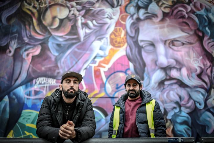 Antonio Sanchez Santos alias Pichi et Alvaro Hernandez Santaeulalia alias Avo,&nbsp;duo d'artistes de rue espagnol PichiAvo,&nbsp;posent devant leur œuvre peinte sur un mur du boulevard Saint-Michel à Paris. (STEPHANE DE SAKUTIN / AFP)