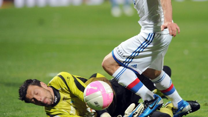 Le gardien auxerrois Olivier Sorin accroche l'attaquant lyonnais Lisandro Lopez lors du match Lyon-Auxerre, le 7 avril 2012. (PHILIPPE MERLE / AFP)