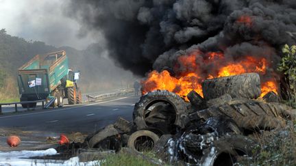 Des agriculteurs bretons br&ucirc;lent des pneus pr&egrave;s de la route, le 14 octobre, lors d'une manifestation &agrave; Morlaix (Finist&egrave;re) en compagnie de salari&eacute;s de diff&eacute;rentes entreprises agroalimentaires. (FRED TANNEAU / AFP)