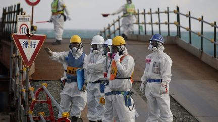 Revêtus de combinaisons de protection et masqués, ces ouvriers ont été vus près des réacteurs 3 et 4 de la centrale de Fukushima lors d'un tour de presse organisé par la Tepco sur le site. Une opération médiatique menée à l'occasion du cinquième anniversaire du séisme et du Tsunami qui s'en est suivi, provoquant un accident nucléaire majeur (classé 7, le niveau le plus élevé) dans la fameuse centrale de l'ouest du Japon, le 11 mars 2011. (TORU HANAI / POOL / AFP)