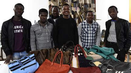 Des migrants posent devant leurs réalisations, des sacs en cuir. Italie, décembre 2017
 (MIGUEL MEDINA / AFP)