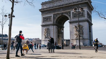 Des passants se promènent à Paris, près de l'Arc de Triomphe, le 21 février 2021. (MATHIEU MENARD / HANS LUCAS / AFP)