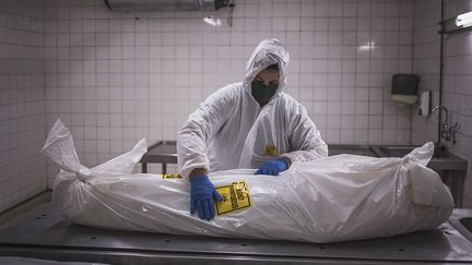 Sur chaque sac plastique blanc hermétiquement noué autour des corps, des autocollants d'un jaune nucléaire indiquent : "Hautement contagieux."&nbsp; &nbsp; (MARCO LONGARI / AFP)