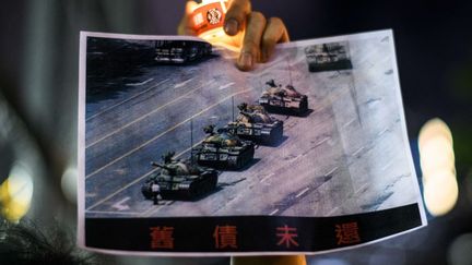 Un homme tient la célèbre photo de "l'homme au char", le 4 juin 2020, lors d'une commémoration à Hong Kong. (ANTHONY WALLACE / AFP)