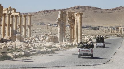 Des soldats de l'armée syrienne passent près de l'Arc de Triomphe de la cité antique de Palmyre (Syrie), le 1er avril 2016. (OMAR SANADIKI / REUTERS)