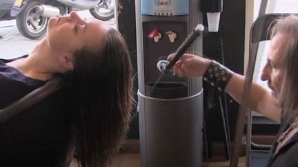 Alberto Olmedo, coiffeur à Madrid (Espagne),&nbsp;coupe les cheveux d'une cliente avec deux katanas, dans une vidéo publiée le 2 décembre 2015 sur Facebook. (AJ+ / FACEBOOK)