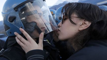 Une jeune fille embrasse un policier &agrave; Suse (Italie), le 16 novembre 2013, lors d'une manifestation contre la future ligne TGV&nbsp;Turin-Lyon. (MARCO BERTORELLO / AFP)