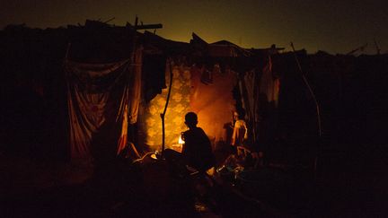 Une femme cuisine dans une tente du centre de r&eacute;fugi&eacute;s de l'a&eacute;roport M'Poko de Bangui (Centrafrique), le 22 f&eacute;vrier 2014. (FRED DUFOUR / AFP)