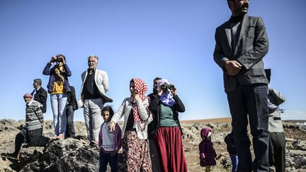 Depuis la fronti&egrave;re avec l'Irak, des Kurdes syriens cherchent &agrave; apercevoir un membre de leur famille parti combattre l'EI &agrave; Koban&eacute; (Syrie), le 20 octobre 2014. (BULENT KILIC / AFP)