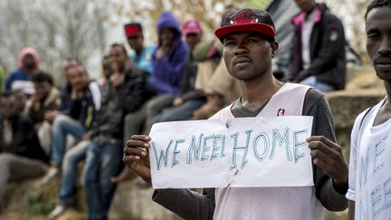 Un migrant tient une pancarte indiquant "nous avons besoin d'un foyer", pendant une visite du ministre de l'Int&eacute;rieur, Bernard Cazeneuve, &agrave; Calais (Pas-de-Calais), le 4 mai 2015. (PHILIPPE HUGUEN / AFP)