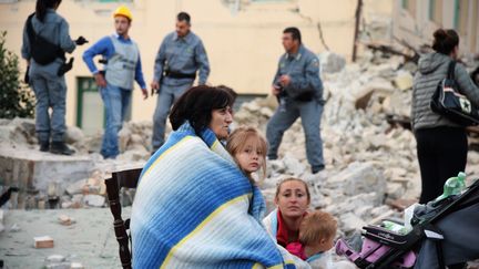 Des habitants sont assis&nbsp;sur les décombres de leur maison, à Amatrice, en Italie (FILIPPO MONTEFORTE / AFP)