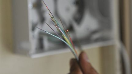 Un technicien en plein branchement montrant des cables de fibre optique. (AFP PHOTO / BERTRAND LANGLOIS)