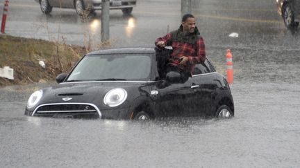 Un automobiliste monte sur le toit de sa voiture, après s'être retrouvé piégé par les eaux, le 5 janvier 2016 en Californie (Etats-Unis).&nbsp; (GENE BLEVINS / REUTERS)