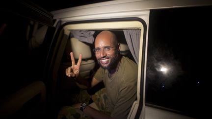 Recherché par la Cour pénale internationale, Seif al-Islam Kadhafi fait le signe de la victoire devant des partisans et des journalistes à Tripoli aux premières heures du 23 août 2011. (DARIO LOPEZ-MILLS / POOL)