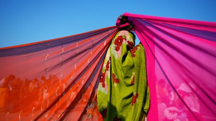 Une femme &eacute;tend des saris pour les faire s&eacute;cher, sur le bord du Sangam, lieu de p&eacute;lerinage &agrave; la&nbsp;confluence du&nbsp;Yamuna, du&nbsp;Ganges&nbsp;et du&nbsp;Saraswati, &agrave;&nbsp;Allahabad, le 10 f&eacute;vrier 2013.&nbsp; (ROBERTO SCHMIDT / AFP)