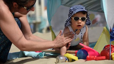 Une mère met de la crème à son enfant, le 26 juin 2018 à Dunkerque (Nord). (MAXPPP)