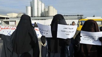 Tunisiennes en niqab tenant des affichettes devant le tribunal de la Manouba, près de Tunis, en solidarité avec des étudiantes portant le voile islamique, pendant le procès du doyen de la faculté locale (3-1-2013).  (AFP - FETHI BELAID)