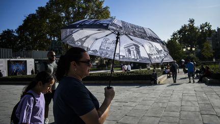 Face aux fortes chaleurs, une passante s'ombrage sous un parapluie, le 2 octobre 2023 à Paris. (MAGALI COHEN / HANS LUCAS / AFP)