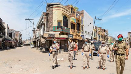 Des policiers indiens veillent à l'application du confinement dans une rue déserte à Amritsar, dans l'Etat du Punjab, le 11 avril 2020. (NARINDER NANU / AFP)