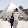 Une femme se protège du soleil à l'aide d'un plan de Paris devant la pyramide du musée du Louvre, le 17 juin 2022. (ALEXIS SCIARD / MAXPPP)