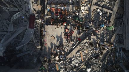 Des Palestiniens inspectent les ruines d'un immeuble après des bombardements israéliens sur le camp de réfugiés Al-Shati dans la bande de Gaza, le 12 octobre 2023. (HATEM MOUSSA / AP / SIPA)