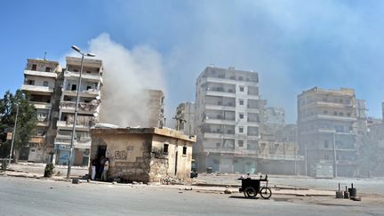 Des habitants se prot&egrave;gent des combats dans une rue d&eacute;gag&eacute;e d'Alep (Syrie), le 25 ao&ucirc;t 2012. (ARIS MESSINIS / AFP)