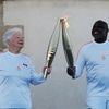 L'ancien footballeur Basile Boli transmet la flamme olympique à Colette Cataldo, le 9 mai 2024, sur les hauteurs de la "Bonne Mère" à Marseille (Bouches-du-Rhône). (RYOHEI MORIYA / YOMIURI / AFP)