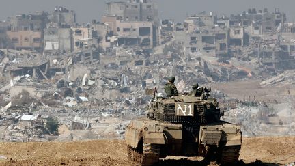 Israeli soldiers face ravaged buildings in the Gaza Strip, January 19, 2024. (JACK GUEZ / AFP)