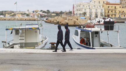 Deux migrants se prom&egrave;nent sur le port de Lampedusa (Italie), le 19 f&eacute;vrier 2015. (ALESSANDRO BIANCHI / REUTERS)