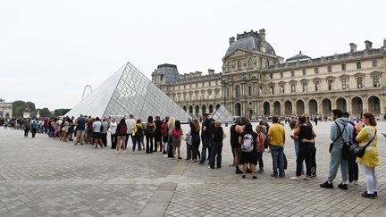 Des visiteurs font la queue pour entrer dans le musée du Louvre, à Paris, le 17 août 2022 (STEFANO RELLANDINI / AFP)