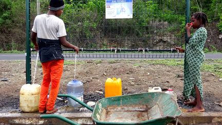 Des enfants remplissent des bouteilles d'eau dans le village de Tsararano, à Mayotte, en décembre 2016. (ORNELLA LAMBERTI / AFP)