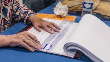 Une personne consulte la liste d'émargement lors des élections européennes, le 9 juin 2024, dans un bureau de vote du Puy-en-Velay (Haute-Loire). (MARIE JULLIARD / HANS LUCAS / AFP)